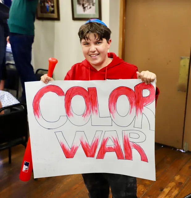 Camper holding a Color War sign